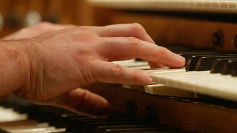 Männliche Hände spielen an einer Orgel