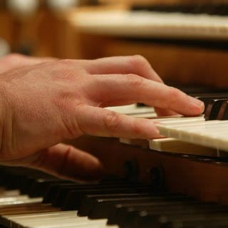 Männliche Hände spielen an einer Orgel