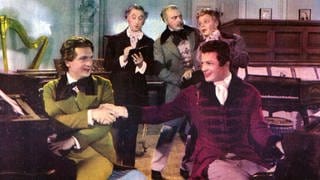 Farb-Werbefoto für den Film "Polonaise" ("A Song to Remember", USA 1945). Franz Liszt (Stephen Bekassy) und Frédéric Chopin (Cornel Wilde) sitzen Rücken an Rücken am Piano und reichen sich freundschaftlich die Hand.