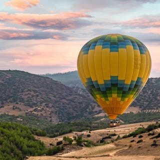 Ein Heissluftballon fliegt über eine weite Ebene. 