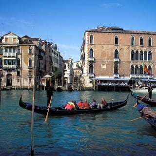 Gondoliere mit Touristen in seiner Gondel auf einem Kanal in Venedig