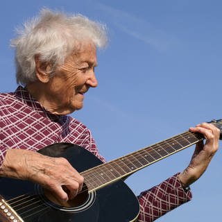 eine ältere Dame spielt Gitarre