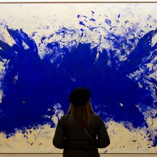 Eine Frau steht vor einem Gemälde des Künstlers Yves Klein