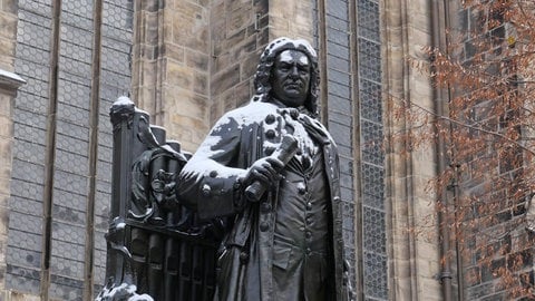 Schneebedecktes Standbild Johann Sebastian Bachs vor der Thomaskirche in Leipzig.