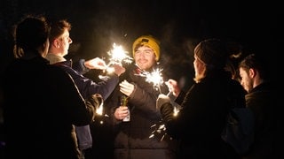 Junge Leute in Edinborough feiern Neujahr auf der Straße mit Wunderkerzen und Sekt