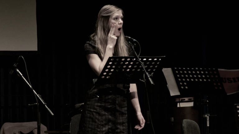 Sängerin legt beim Singen zwei Finger auf ihre Wange