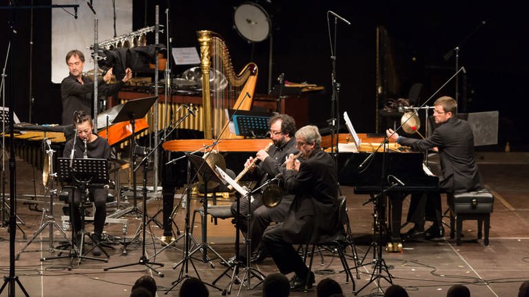 Fünf Musiker vom ensemble recherche beim Konzert auf der Bühne