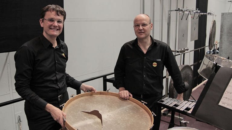 Zwei Schlagzeuger des SWR Symphonieorchesters vor gerissenem Paukenfell