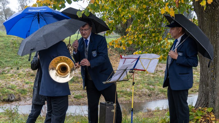 Musikvereinsmitglieder im Freien unter Regenschirmen