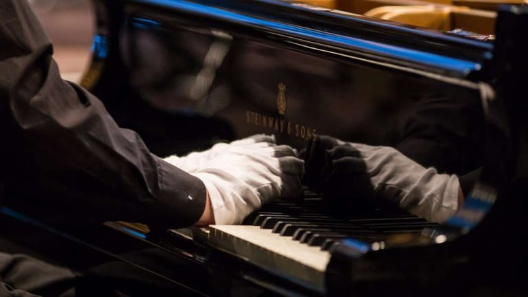 Klavier wird mit Handschuhen gespielt