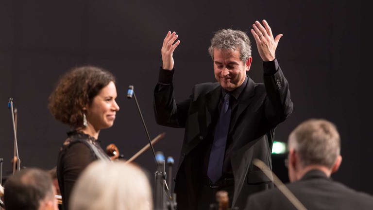 Dirigent bedankt sich bei Musikerin vom Orchester