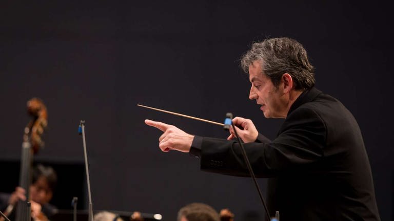 Mann mit Dirigentenstab leitet Orchester bei Eröffnungskonzert