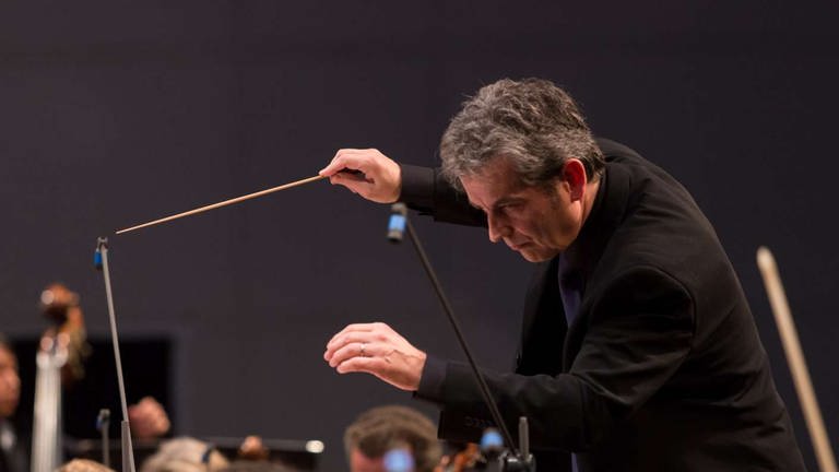 Mann leitet Orchester mit Dirigierstab