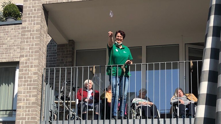 Frau wirft Papierflieger von Balkon