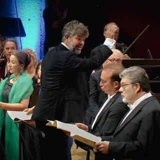 Pablo Heras-Casado dirigiert das SWR Symphonieorchester in der Stuttgarter Liederhalle. Im Vordergrund die Solist*innen Christina Landshamer, Daniel Behle und Franz-Josef Selig