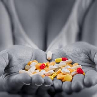 Eine Frau hält verschiedene Tabletten in ihren Händen.