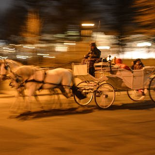 Wiener Fiaker mit Fahrgästen in der Nacht bei schneller Fahrt