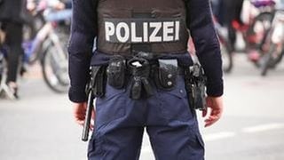 Polizist in Berlin mit Schutzweste, Pistole, Schlagstock und Handschellen am Gürtel