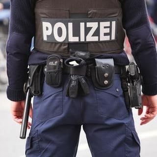 Polizist in Berlin mit Schutzweste, Pistole, Schlagstock und Handschellen am Gürtel