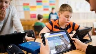Schüler einer 5. Klasse lernen im Englischunterricht mit iPads