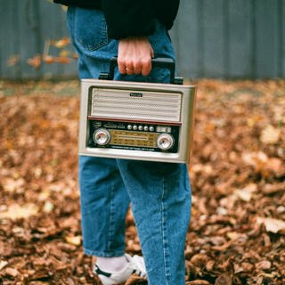 Ein Mann hat ein Radio in der Hand, das er im Freien trägt 