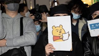 Eine Demonstrierende mit einem Winnie The Pooh Bild gegen die chinesische Obrigkeit