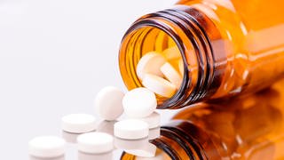 Braunes Fläschchen mit ausgekippten Tabletten: Placebos wirken, das ist mittlerweile belegt. Die Erwartung, ein Medikament zu erhalten, löst in vielen Patienten Selbstheilungskräfte aus.