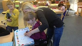 Eine Lehrerin hilft einer Schülerin in der Körperbehindertenschule in Kronau