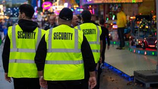 Mitarbeiter eines privaten Sicherheitsdiensts gehen zu Beginn des 174. Cannstatter Volksfests über das Gelände