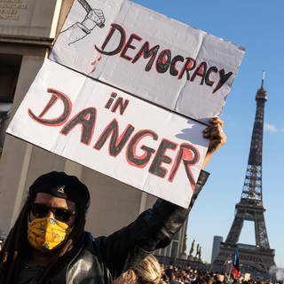 Plakat mit der Aufschrift "Democracy in danger", daneben der Eiffelturm: Demonstration gegen das globale Sicherheitsgesetz am 21. November 2020 in Paris  Frankreich