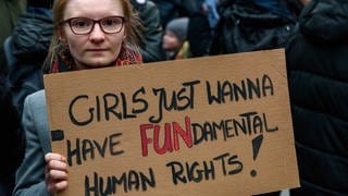 Frau hält Pappschild mit der Aufschrift: "Girls just wanna have FUNdamental Human Rights!": Solidaritäts-Kundgebung 2018 an der Warschauer Brücke in Berlin gegen die Verschärfung der Gesetze in Polen bei Schwangerschaftsabbrüchen 