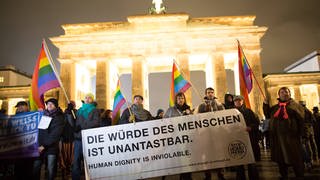 "Die Würde des Menschen ist unverletztlich" steht auf dem Transparent bei einer Demonstration vor dem Brandenburger Tor