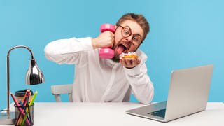 Mann am Laptop isst und "telefoniert" mit einer Hantel am Ohr: Oft heißt es in Medienberichten: Die Aufmerksamkeitsspanne schrumpft, es gelingt uns immer seltener, uns über längere Zeit zu konzentrieren, ohne uns ablenken zu lassen.