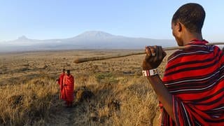 Massai mit Mount Kilimanjaro und Mount Mawenzi (in Tansania) links im Hintergrund