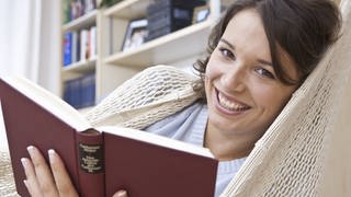 Ein Frau liest in der Hängematte: Lesen soll den Blutdruck senken, das Gehirn fit halten und sogar unser Leben verlängern. Was ist dran an diesen Thesen?