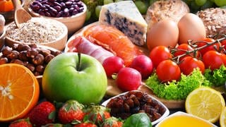 Reich gedeckter Tisch mit Obst, Gemüse, Nüssen, Eiern, Käse, Getreideprodukten: "Die" gesunde Ernährung für alle gibt es nicht. Aber immer noch gilt: Abwechslung und Mäßigung, wenig rotes Fleisch, wenig Fett und Zucker. 