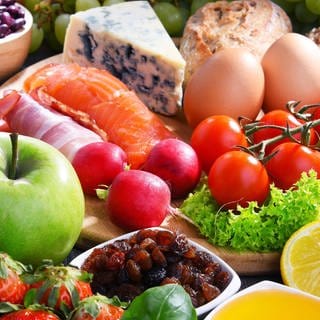 Reich gedeckter Tisch mit Obst, Gemüse, Nüssen, Eiern, Käse, Getreideprodukten: "Die" gesunde Ernährung für alle gibt es nicht. Aber immer noch gilt: Abwechslung und Mäßigung, wenig rotes Fleisch, wenig Fett und Zucker. 