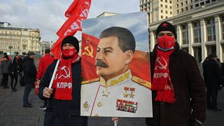 Am Todestag von Stalin, der am 5. März 1953 starb, nehmen im März 2022 Mitglieder der Kommunistischen Partei Russlands an einer Blumenniederlegungszeremonie am Grab des sowjetischen Führers Joseph Stalin an der Kremlmauer teil. Vor sich tragen sie ein Porträt Stalins.