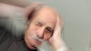 Ein älterer Mann fasst sich an seinen Kopf: Rund 30 Prozent aller Menschen in Deutschland erleben irgendwann in ihrem Leben Schwindel, auch Vertigo genannt, egal, wie alt sie sind. 