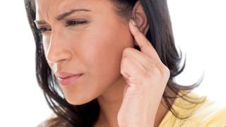 Junge Frau mit Ohrproblemen verzieht das Gesicht: Einen Tinnitus bekommt man nicht weg, aber man kann über eine kognitive Verhaltenstherapie erreichen, dass man mit dem Tinnitus besser klarkommt. 