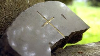Kaputter Grabstein mit einem Kreuz