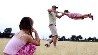 Ein Mädchen schaut traurig zu, wie Vater und Schwester spielen.