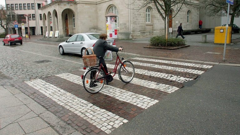 Eine Frau schiebt am Marktplatz von Sindelfingen ihr Fahrrad über einen Zebrastreifen aus italienischen Carrara-Marmor. Lange war die Stadt vor den Toren Stuttgarts die reichste deutsche Kommune und konnte sich marmorne Zebrastreifen leisten. 