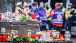 Blumen und Kerzen, im Hintergrund Menschen: Trier trauert am Mittwoch 02.12.2020 in der Fussgängerzone um die Opfer der Amokfahrt vom Vortag. Der mutmaßliche Amokfahrer ist einem psychiatrischen Gutachten zufolge vermindert schuldfähig. Am 16. August 2022 wird das Urteil erwartet.