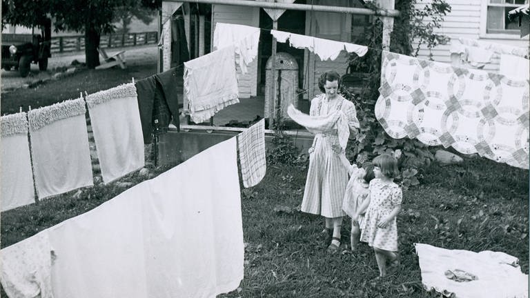 ... galt die Hausfrau in westlichen Ländern als Statussymbol. Hier: Ada Martin mit ihren Töchtern Jo Ann und Linda um 1950 beim Aufhäengen der Wäsche im Garten hinter dem Farmhaus in Lancaster  Kentucky (USA)