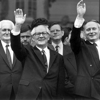 Geinsam winken der saarländische Ministerpräsident Oskar Lafontaine (rechts) und sein Gast, der DDR-Staatsratsvorsitzende und SED-Chef Erich Honecker (Mitte) nach der Besichtigung der barocken Ludwigskirche am 10.9.1987 in Saarbrücken den rund 100 Zuschauerrn zu. Links steht Honeckers Stellvertreter Günter Mittag.