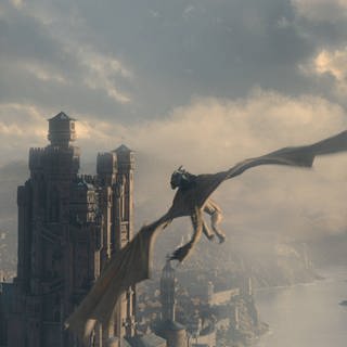 Ein Drache fliegt auf eine Burg zu in der Serie "House of the Dragon"