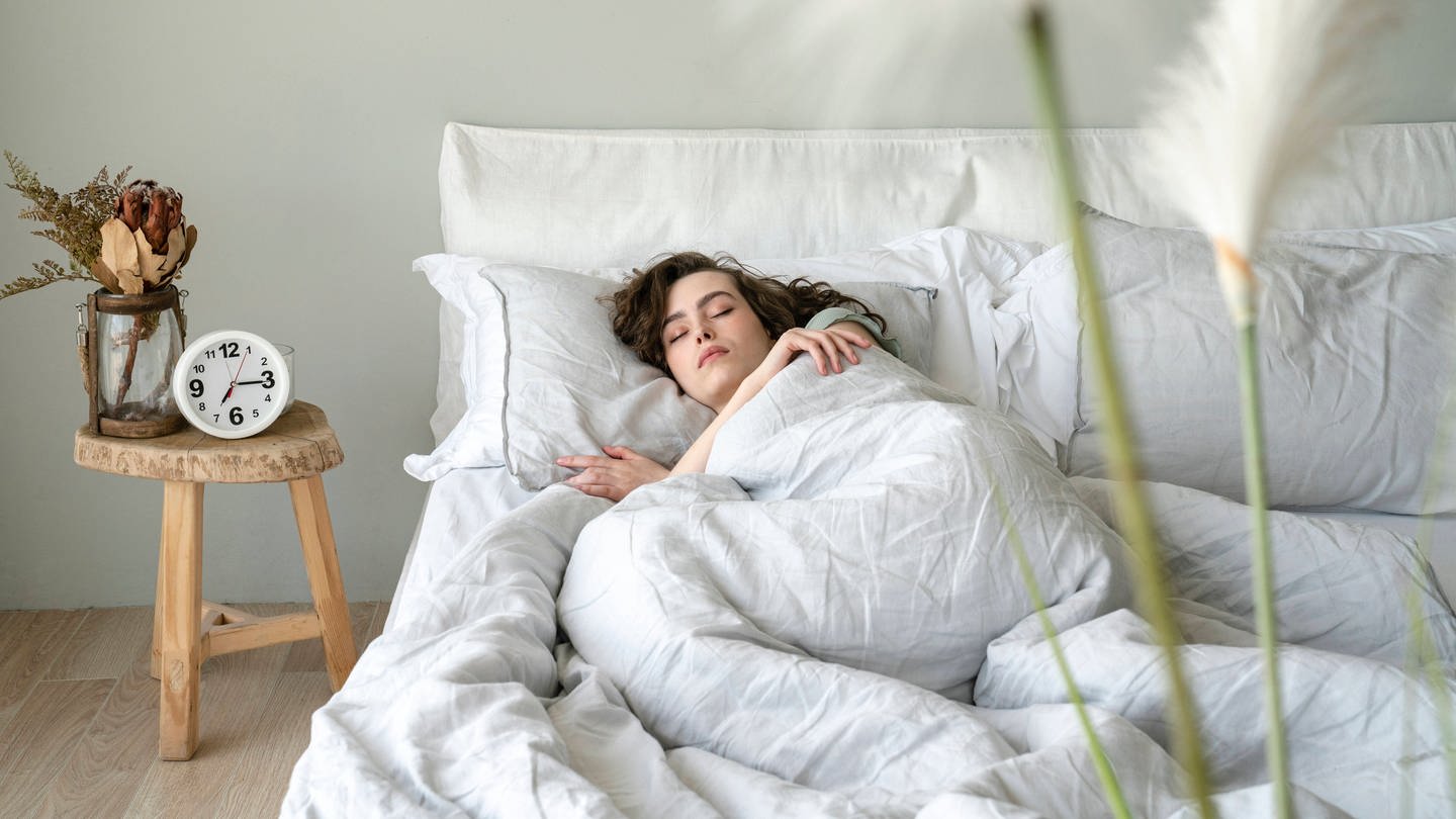 Eine junge Frau liegt im Bett und schläft friedlich