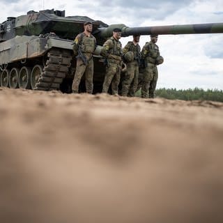 Ein Leopard 2 Panzer der Bundeswehr der NATO Enhanced Forward Presence Battle Group (eFP-Bataillon) steht beim Besuch von Kanzler Scholz im Camp Adrian Rohn. Kaum ein Waffensystem hat eine derartige Revolution ausgelöst wie der Panzer. Heute sind es Hochleistungsmaschinen, wesentlich schneller als ihre Vorgänger vor 100 Jahren – und durch den Angriffskrieg Russlands auf die Ukraine im Fokus der aktuellen Diskussion.