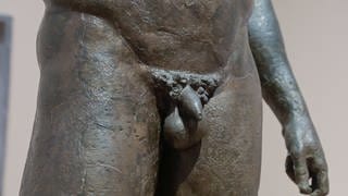 Die Detailaufnahme des Penis einer antiken Bronzestatue